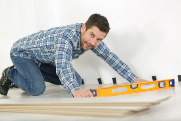 man with spirit level on stripped wooden floorboards