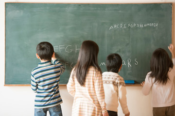 黒板にアルファベットを書く小学生