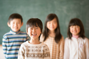 黒板の前で微笑む小学生