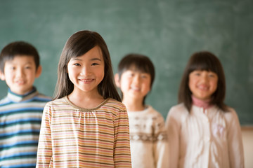 黒板の前で微笑む小学生