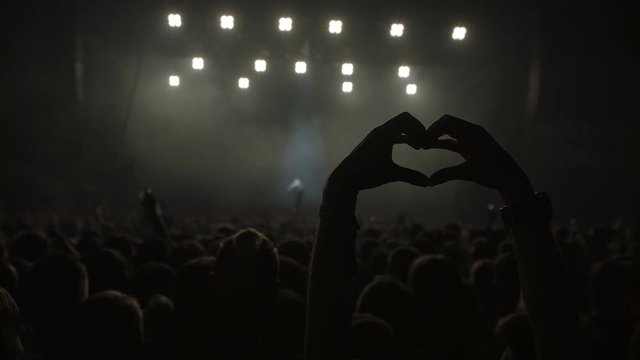 person showing a heart with hands on a live concert