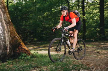 Mountain biker riding on bike in spring inspirational forest landscape. Man cycling MTB on enduro trail track. Sport fitness motivation and inspiration.