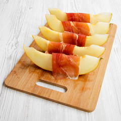 Melon slices wrapped in prosciutto, low angle view. Close-up.