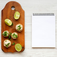 Mushroom and chicken puree, lime and notebook on a white wooden surface, top view. Flat lay, overhead. Copy space.