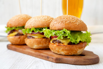 Homemade cheeseburgers on rustic wooden board and glass of cold beer, side view. Closeup. Selective focus.