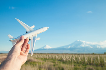 Hand holding airplane model in front of Ararat mountain background. Travel, Armenia