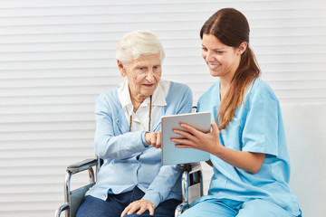 Neugierige Seniorin im Rollstuhl mit Tablet PC
