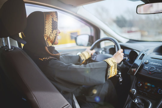Gorgeous smiling muslim woman dressed in traditional wear driving her car.