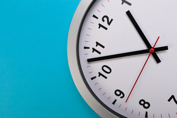 Closeup wall clock set on blue background. The concept of " The time is going on." Top view with Selective focus. Copy space.