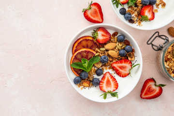  Homemade granola  with yogurt and fresh strawberry, blueberry and blood orange in white bowl. Healthy breakfast.