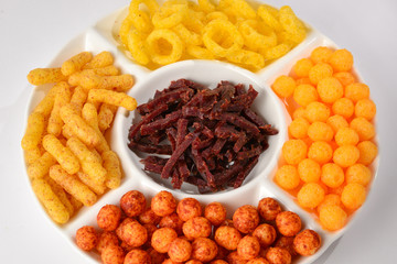Mix of snacks on a white plate isolated on white.