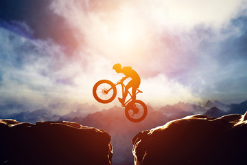 Man jumping with bike between two high mountains