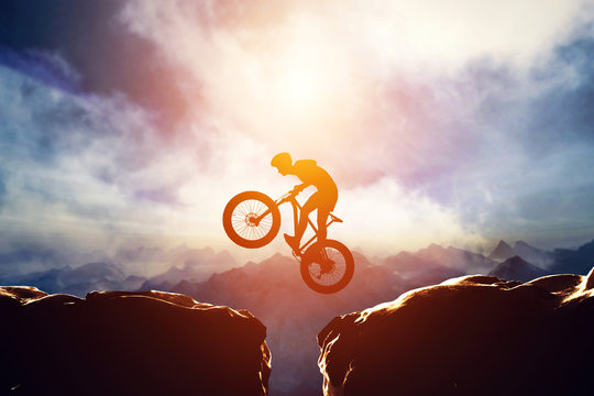 Man jumping with bike between two high mountains