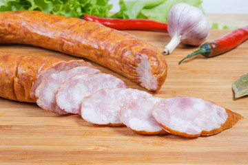 Partly sliced bologna sausage among some spices close-up © An-T