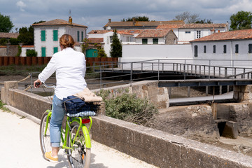 riding tourist woman on bicycle at the coast on village on Ile de Ré island in France west