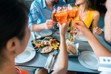 Four friends toasting together with a cold refreshing alcoholic drink