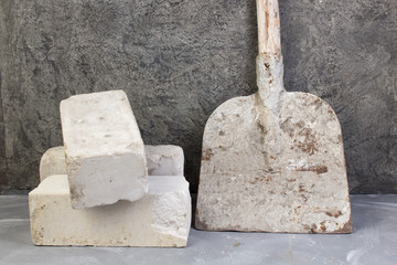 bricks, old, dirty shovel on the gray concrete background. Copy space. Top view.