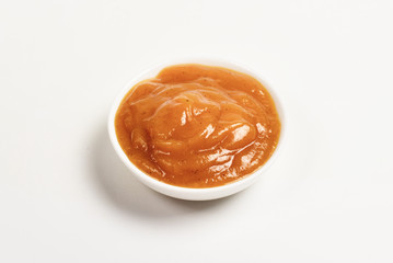 Orange sauce in white plate on white background.