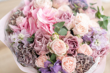 Beautiful bouquet of mixed flowers on wooden table. the work of the florist at a flower shop. Delicate Pastel color. Fresh cut flower. Pink and lilac color