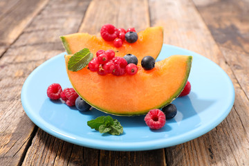 melon with berries fruits on wood background