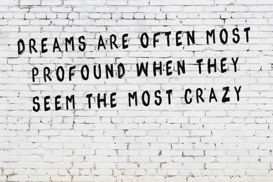 White brick wall with painted black motivational quote inscription