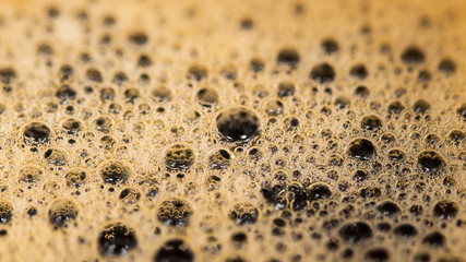 Coffee surface texture. Foam bubbles in detail. Aromatic hot drink. Abstract frothy background. Mirroring in bubbly brown fluid. Fragrant energizing beverage with caffeine. Side view. Selective focus.
