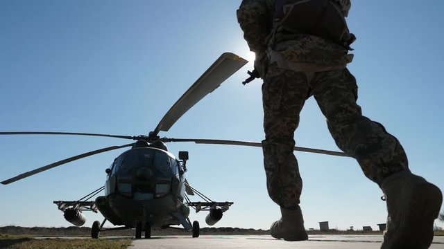 Modern soldiers running to a helicopter on a helicopter pad in spring in slo-mo