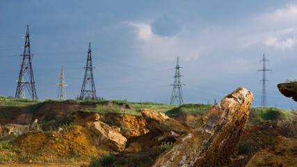 Stones in the foreground. Quarry and high-voltage towers.Powerful lines of electric gears.Electric power industry and nature concept.High voltage power lines.