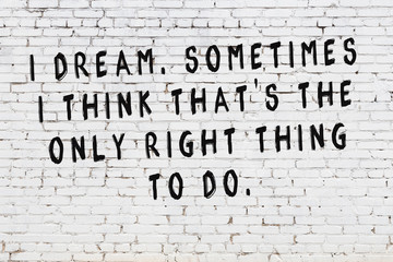 White brick wall with painted black motivational quote inscription