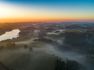 Foggy sunrise over forests and lakes - view from above
