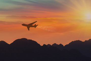 Fototapeta na wymiar Silhouette, Airplane in the sky under mountains at sunset. Copy space