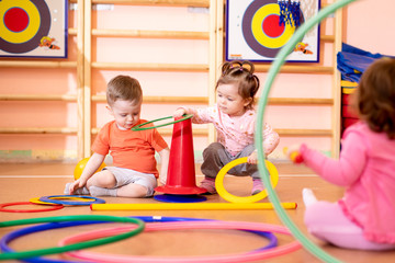 Nursery babies toddlers group play with rings in gym - 267535965