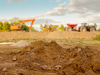 Construction site, Selective focus, Pile of soil in foreground in focus, machinery in the...