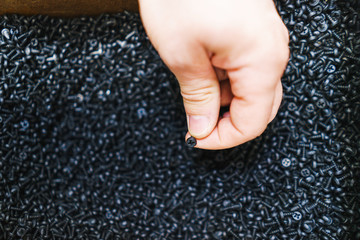 Man holds in his hands small screws for repair and fasteners in a box close-up.