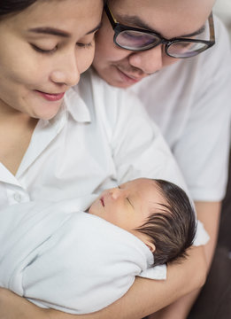 Asian Parents With Newborn Baby, Close Up Portrait Of Asian Young Couple Father And Mother Holding Their New Born Baby. Happy Family Love Newborn Nursery Mother’s Day Holiday Concept