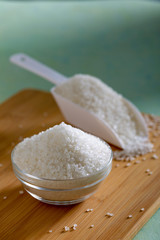 Sugar in glass bowl on wooden background