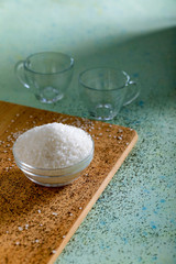 Sugar in glass bowl on wooden background