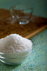 Sugar in glass bowl on wooden background