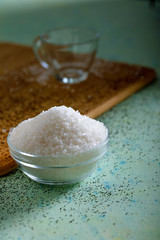 Sugar in glass bowl on wooden background