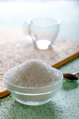 Sugar in glass bowl on wooden background