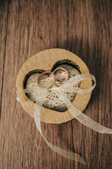 wedding rings in a box in the shape of a heart on an isolated wooden background