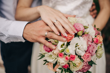 the groom hugs the bride by the waist, and she is holding a wedding bouquet