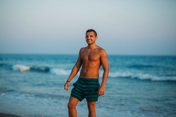 Handsome man walking on the coast in sunset. Background of beautiful sea