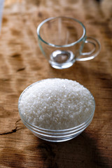 Sugar in glass bowl on wooden background