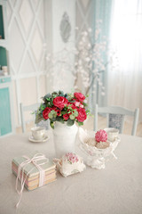 Vintage table served for tea drinking in bright colors. Vase with pink cupcakes. A bouquet of flowers and a stack of books. Morning in the country