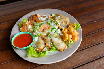 Stir-fried rice noodle with chicken, squid, fry egg and lettuce