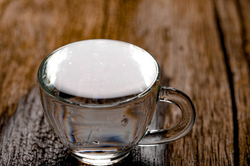 water in cup on wooden background 