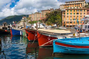 Fototapeta premium View of the town of Camogli on the Ligurian Riviera in Italy with its port. In the foreground, the typical colored fishing boats.