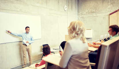 education, high school, university, teaching and people concept - group of students and teacher with marker standing at white board at lecture