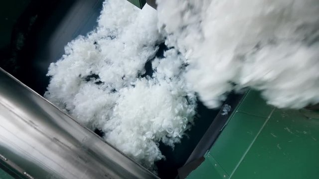 White polyester fabric falls from a conveyor at a plant.